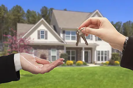 real estate agent handing over the keys in front new home
